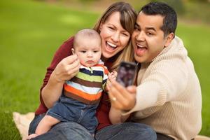 felices padres de raza mixta y niño tomando autorretratos foto