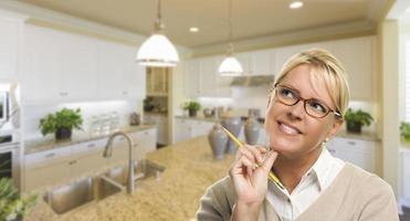 Daydreaming Woman with Pencil Inside Beautiful Kitchen photo
