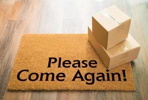 Please Come Again Welcome Mat On Wood Floor With Shipment of Boxes photo