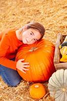 niña abrazando una gran calabaza en el huerto de calabazas. foto