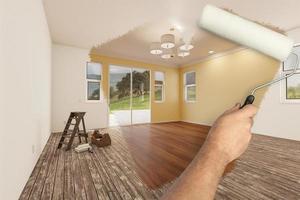 Before and After of Man Painting Roller to Reveal Newly Remodeled Room with Light Yellow Paint and New Floors. photo