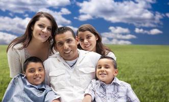 Hispanic Family Portrait Sitting in Grass Field photo