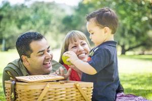 familia de raza mixta disfruta de un picnic en el parque foto