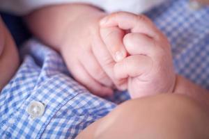Close-up Of Infant Hands While Laying on Lap of Mother photo