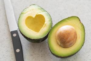 aguacate recién cortado con área de hoyo en forma de corazón en tabla de cortar de madera foto