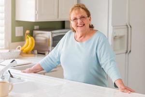 Portrait of A Beautiful Smiling Senior Adult Woman in Kitchen photo