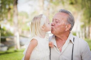 abuelo y nieta besándose en el parque foto