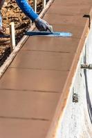Construction Worker Using Trowel On Wet Cement Forming Coping Around New Pool photo