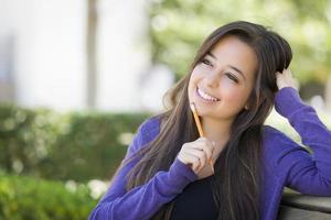 Pensive Mixed Race Female Student with Pencil on Campus photo