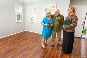 agente inmobiliaria femenina entregando llaves de casa nueva a una pareja de adultos mayores en un nuevo hogar foto