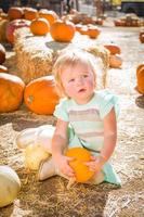 adorable niña divirtiéndose en un rancho rústico en el huerto de calabazas. foto