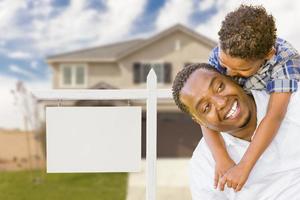 African American Father and Mixed Race Son In Front of Blank Real Estate Sign and House photo