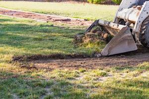 excavadora pequeña quitando hierba del patio preparándose para la instalación de la piscina foto