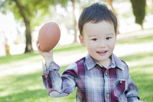 Cute Young Mixed Race Boy Playing Football Outside photo