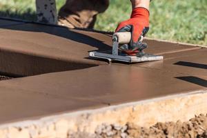 Construction Worker Using Hand Groover On Wet Cement Forming Coping Around New Pool photo