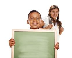 niño y niña hispanos sosteniendo una pizarra en blanco sobre blanco foto