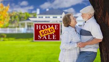 Sold Real Estate Sign with Senior Couple in Front of House photo