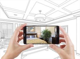 Hands Holding Smart Phone Displaying Photo of Bedroom Drawing Behind