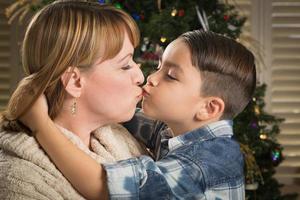 Mother and Mixed Race Son Hug Near Christmas Tree photo