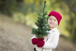 Baby Girl In Red Mittens and Cap Holding Small Christmas Tree photo