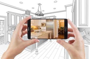 Hands Holding Smart Phone Displaying Photo of Kitchen Drawing Behind