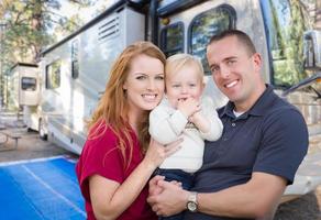 Happy Young Military Family In Front of Their Beautiful RV At The Campground. photo