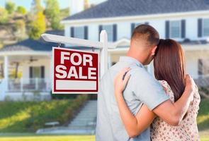 Military Couple Looking At House with For Sale Real Estate Sign In Front photo