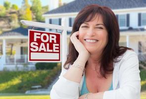 Middle Aged Woman In Front of House with For Sale Real Estate Sign In Yard photo