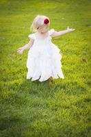 Adorable Little Girl Wearing White Dress In A Grass Field photo