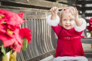 Adorable Little Girl Sitting On Bench with Her Candy Cane photo