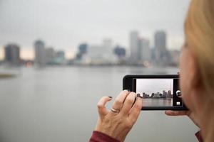 mujer tomando fotos del horizonte de nueva orleans con su teléfono inteligente