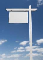 Blank Real Estate Sign Over A Blue Sky with Clouds. photo