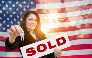 Hispanic Woman House Keys and Sold Sign In Front of American Flag photo