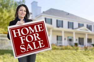 Woman Holding Home For Sale Sign in Front of House photo