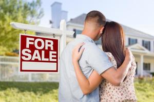 Señal de venta de bienes raíces, pareja militar mirando la casa foto