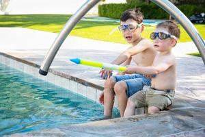 Young Mixed Race Chinese and Caucasian Brothers Wearing Swimming Goggles Playing At The Pool photo