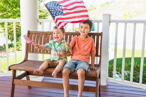 jóvenes mestizos chinos y caucásicos hermanos jugando con banderas americanas foto