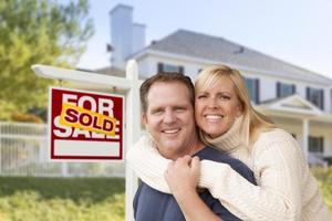 Couple in Front of New House and Sold Sign photo