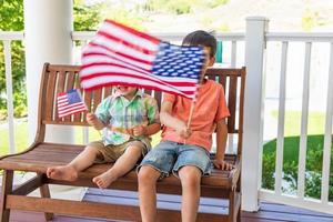 jóvenes mestizos chinos y caucásicos hermanos jugando con banderas americanas foto