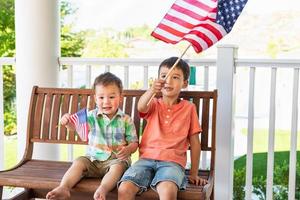 jóvenes mestizos chinos y caucásicos hermanos jugando con banderas americanas foto