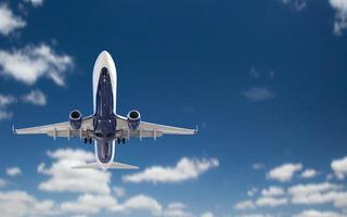 vista inferior del avión de pasajeros volando en el cielo azul foto