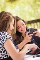 Expressive Young Adult Girlfriends Using Their Computer Electronics Outdoors photo