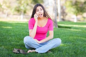 Beautiful Young Ethnic Woman Talking on Her Smartphone Outside. photo