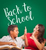 Back To School Written On Chalk Board Behind Hispanic Young Boy and Famale Adult Studying photo