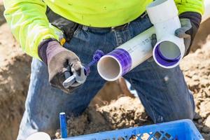 fontanero aplicando limpiador de tuberías, imprimación y pegamento a la tubería de pvc en el sitio de construcción foto