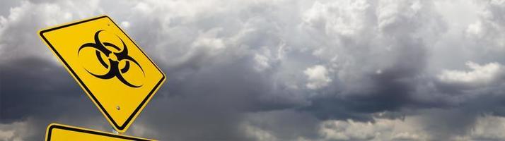Señal de carretera amarilla de riesgo biológico contra la ominosa pancarta de cielo nublado tormentoso foto