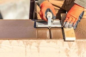 Construction Worker Using Hand Groover On Wet Cement Forming Coping Around New Pool photo