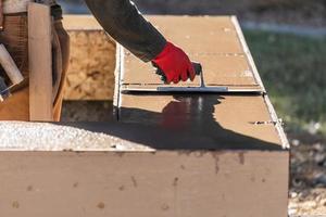 trabajador de la construcción usando paleta sobre cemento húmedo formando afrontamiento alrededor de la nueva piscina foto