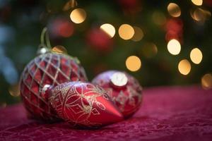 Elaborate Christmas Ornaments Resting on Table In Front of Lit Tree photo