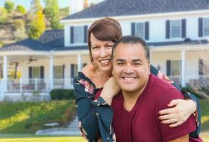 retrato de una pareja adulta joven de raza mixta frente a una hermosa casa foto